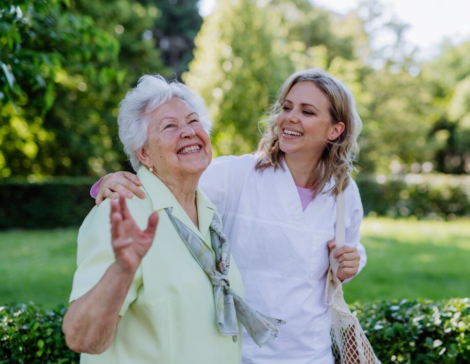 Smiling happy carer and elderly woman in the park